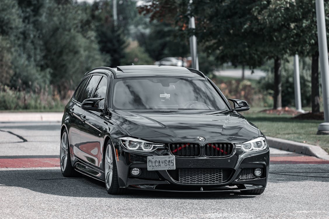 Black BMW luxury sedan on a tree-lined road